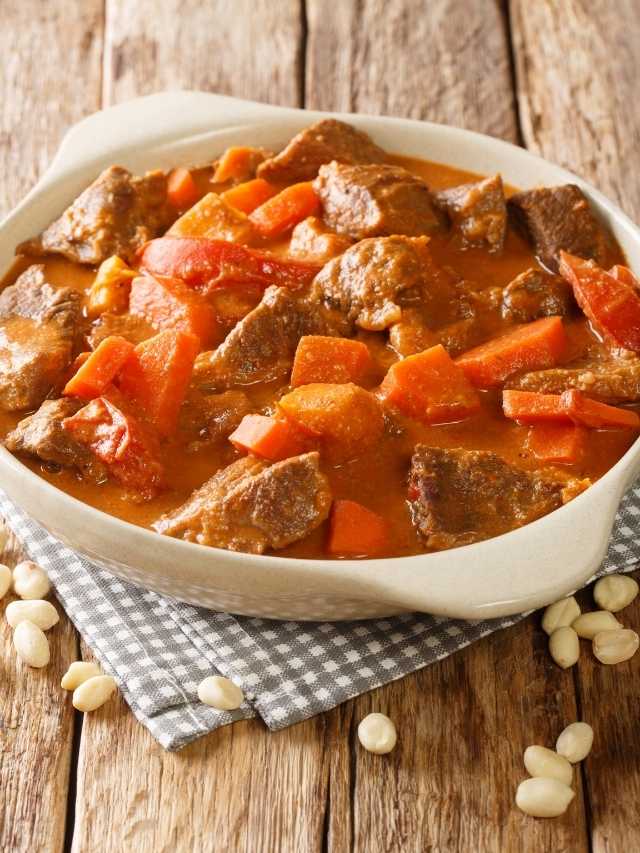 Beef stew in a white bowl on a wooden table.