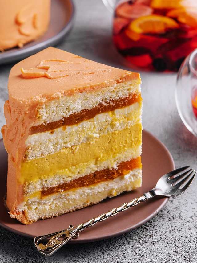 A slice of orange cake on a plate with a fork.