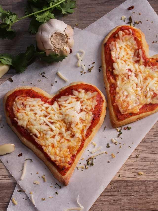 Two heart shaped pizzas with cheese and garlic.