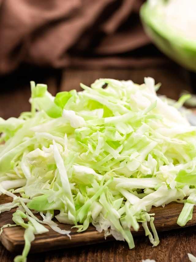 Shredded cabbage on a wooden cutting board.
