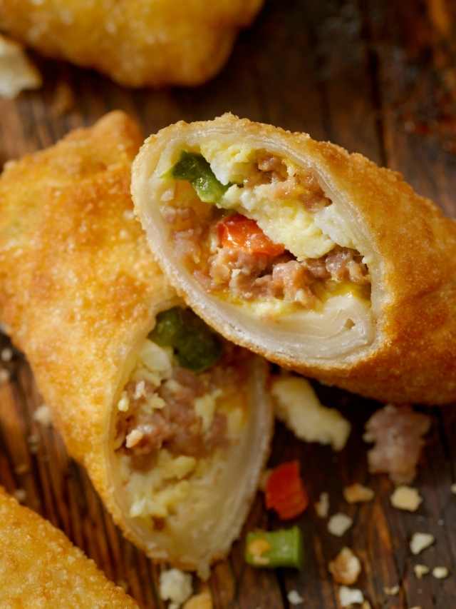 Chinese egg rolls with meat and vegetables on a wooden cutting board.