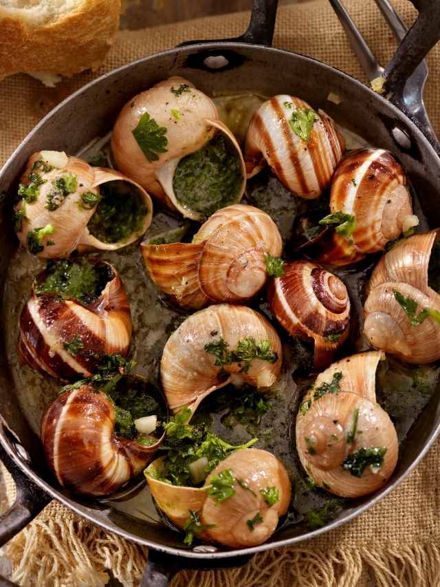 Snails in a pan with herbs and bread.