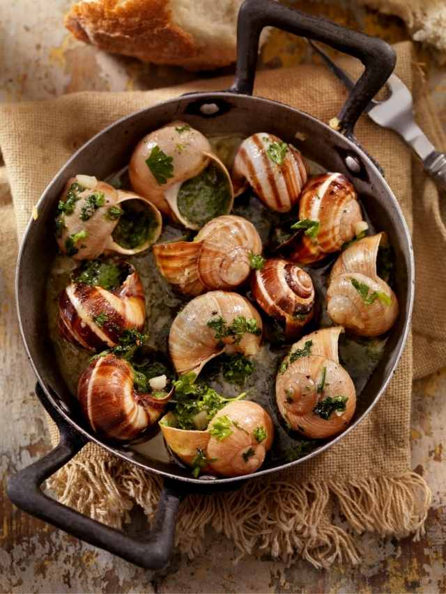 Snails in a pan with herbs and bread.