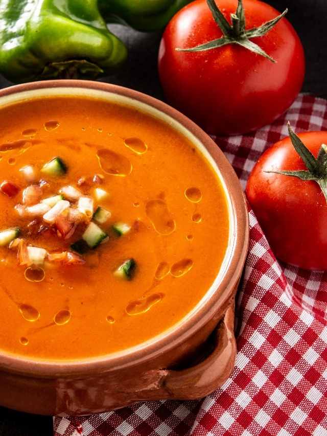 A bowl of tomato soup with peppers and tomatoes.