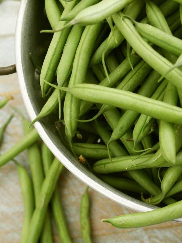 Green beans in a bowl on a wooden table.