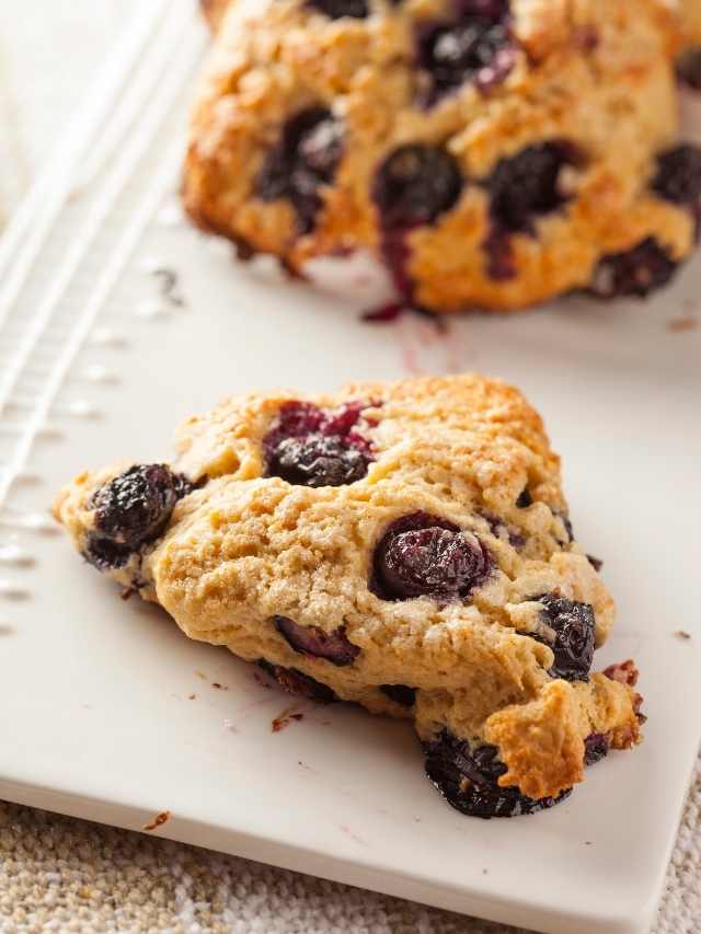 Blueberry scones on a white plate served with savory accompaniments.