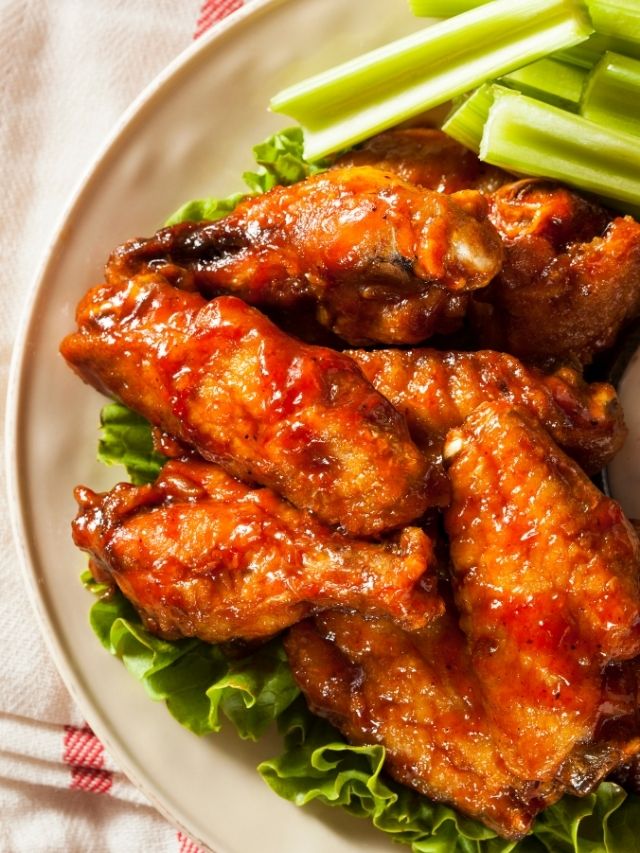 Chicken wings on a plate with celery sticks.