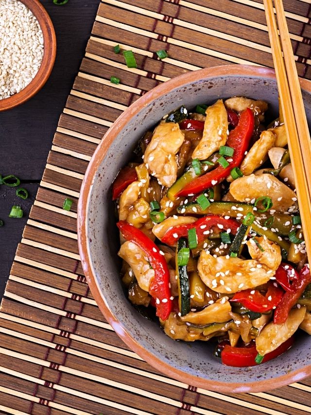 A bowl of stir fried chicken with peppers and sesame seeds, inspired by the popular Panda Express sesame chicken recipe.