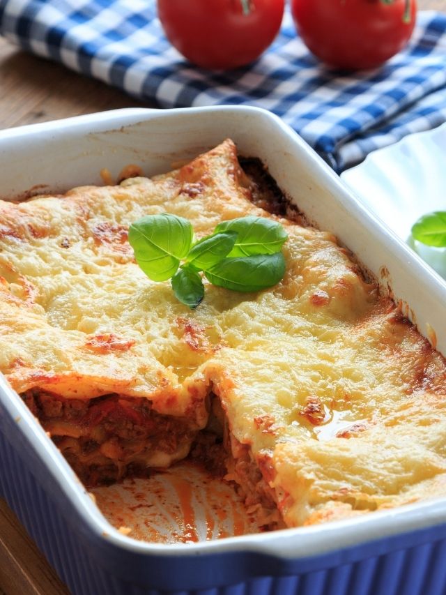 Lasagna in a dish with tomatoes and basil.