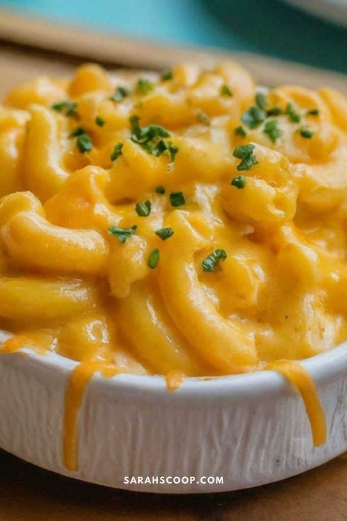 A bowl of creamy macaroni and cheese garnished with chopped herbs.